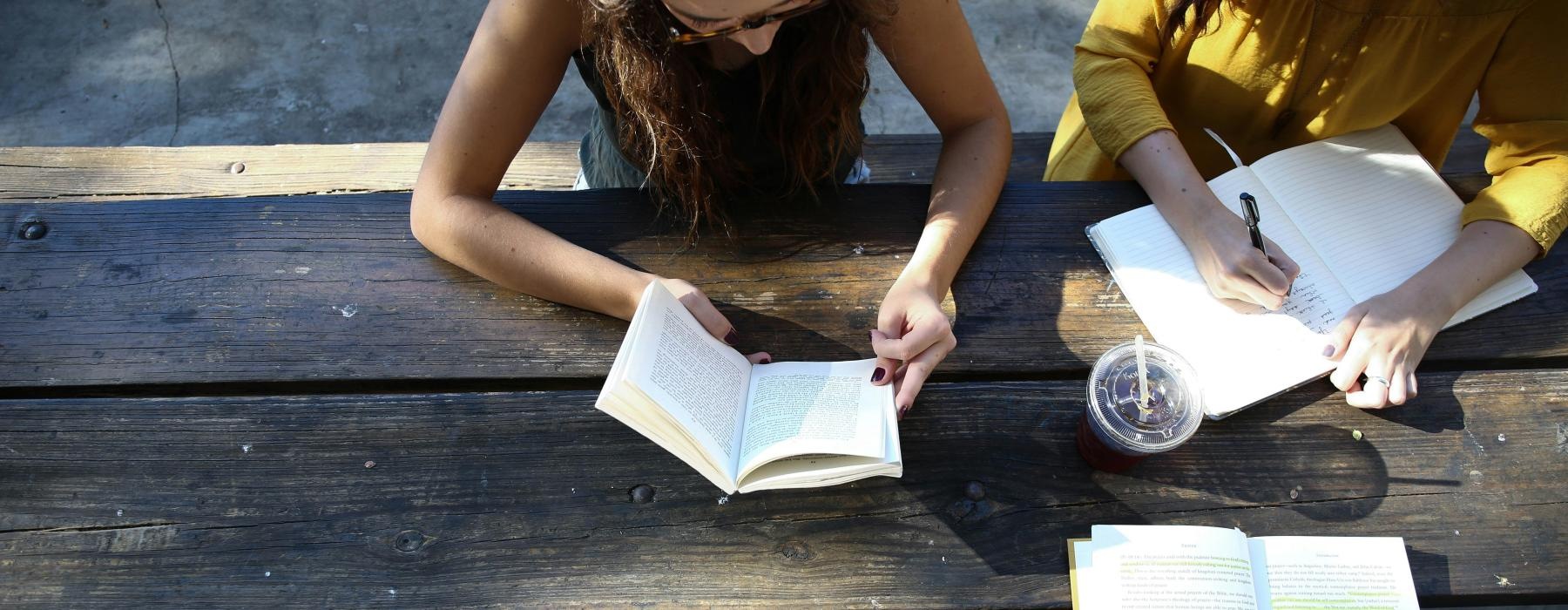 a few people studying on a wooden table