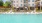  A large swimming pool in front of a white apartment building.