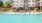  A large swimming pool in front of a white apartment building.