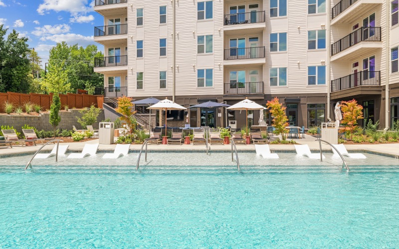  A large swimming pool in front of a white apartment building.