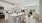White kitchen with stainless steel appliances connected to a living room