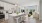 White kitchen with stainless steel appliances connected to a living room